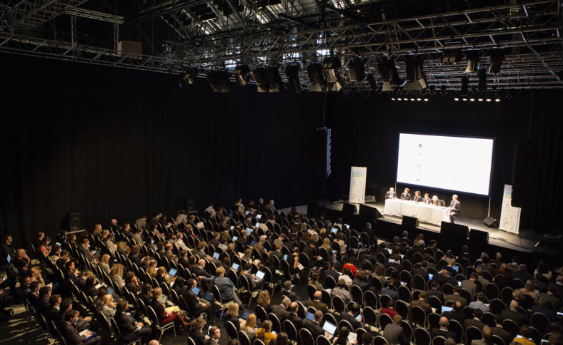 Großer Konferenzsall mit vielen vollen Stühlen.