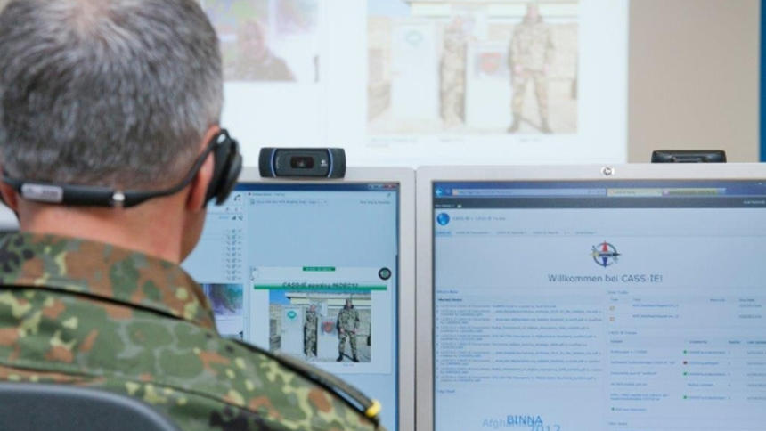 Ein Mann in Bundeswehr-Uniform sitzt vor PC-Bildschirmen