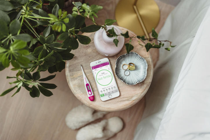 Ein Thermometer und ein Smartphone liegen auf dem Nachttisch