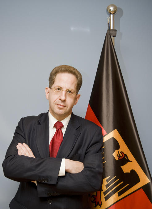 Hans-Georg Maaßen mit gekreuten Armen vor der Deutschlandflagge