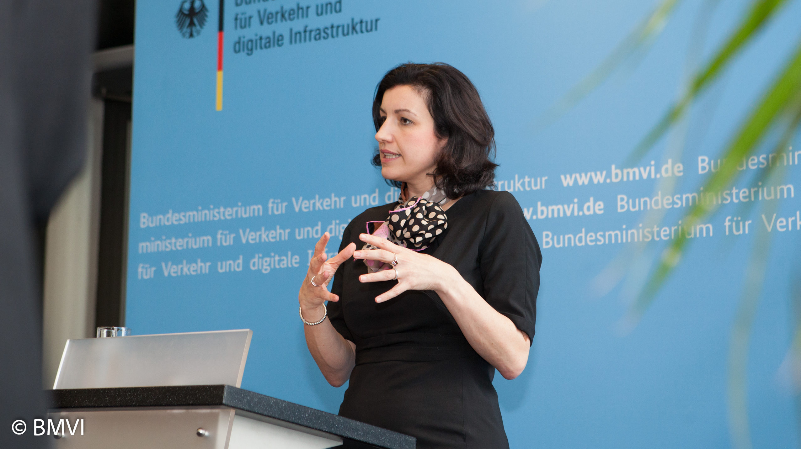 Dorothee Bär vor einer blauen Wand an einem Rednerpult beim Sprechen