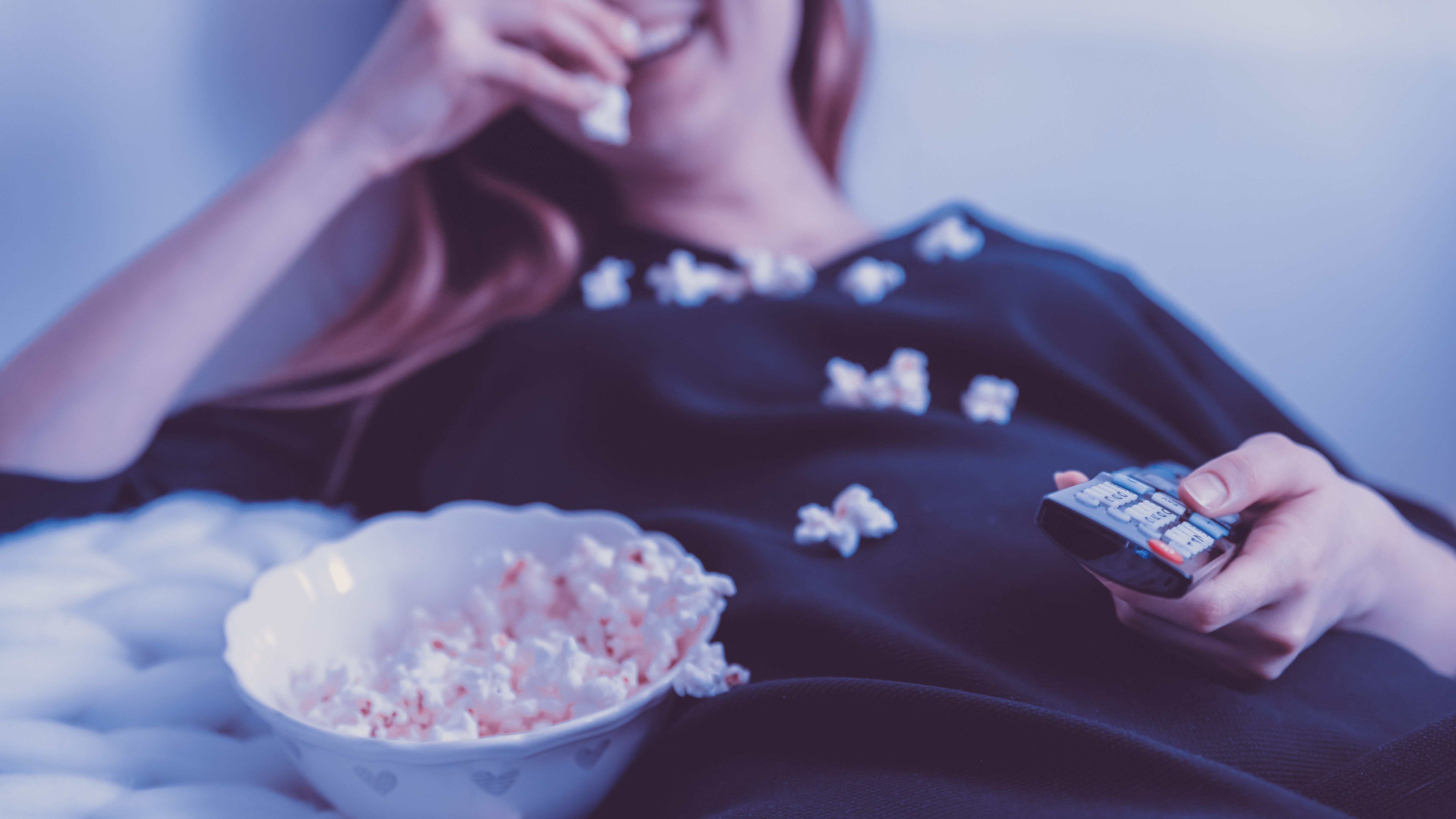 Frau beim Popcornessen auf dem Bett