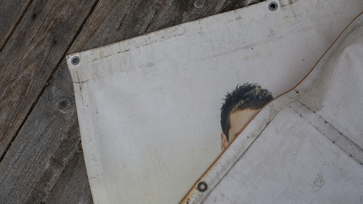 Mann versteckt sich hinter Plakat