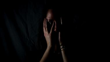 Eine Frau hält sich die Hände vor das Gesicht, schwarzer Hintergrund