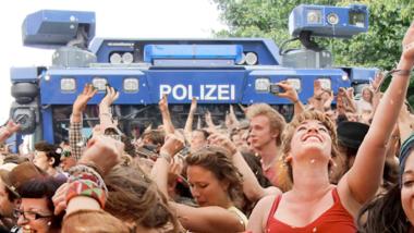 Tanzende Leute, im Hintergrund ein blauer Wasserwerfer der deutschen Polizei