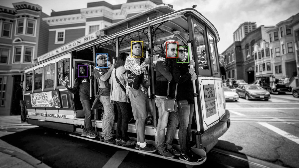 Menschen fahren mit der Straßenbahn in San Francisco. Ihre Gesichter sind mit bunten Kästen markiert, die Gesichtserkennung symbolisieren soll.