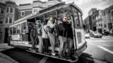 Menschen fahren mit der Straßenbahn in San Francisco. Ihre Gesichter sind mit bunten Kästen markiert, die Gesichtserkennung symbolisieren soll.