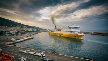 Eine gelbe Fähre im Hafen von Bastia. Aus dem Schornstein steigt Rauch auf.