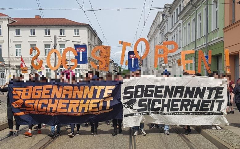 Demonstrierende mit großen Transparenten auf der Straße in Rostock