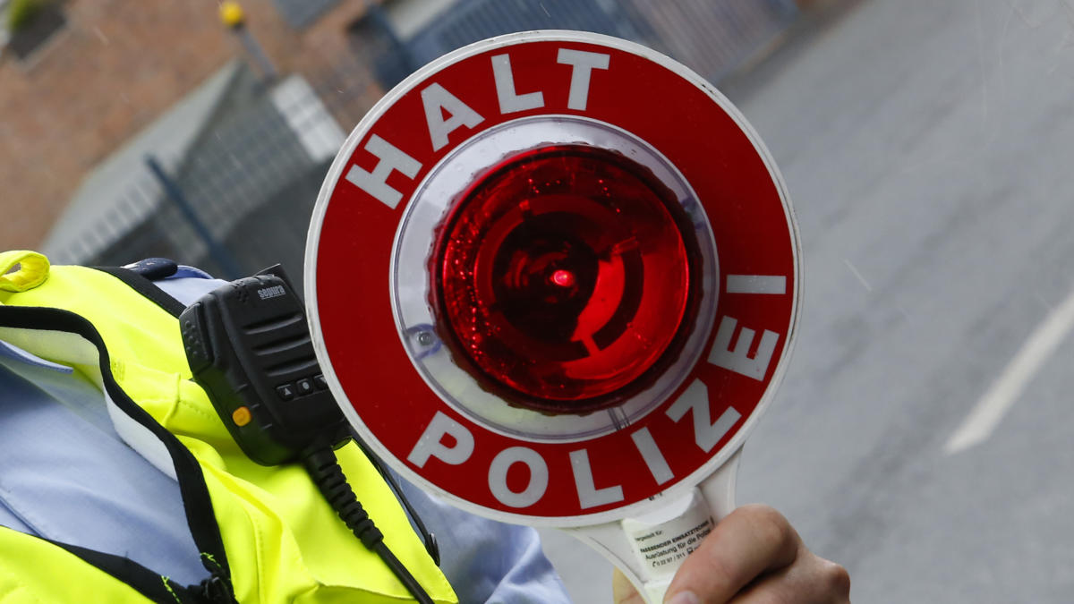 Person mit Warnweste hält Polizeikelle in die Kamera