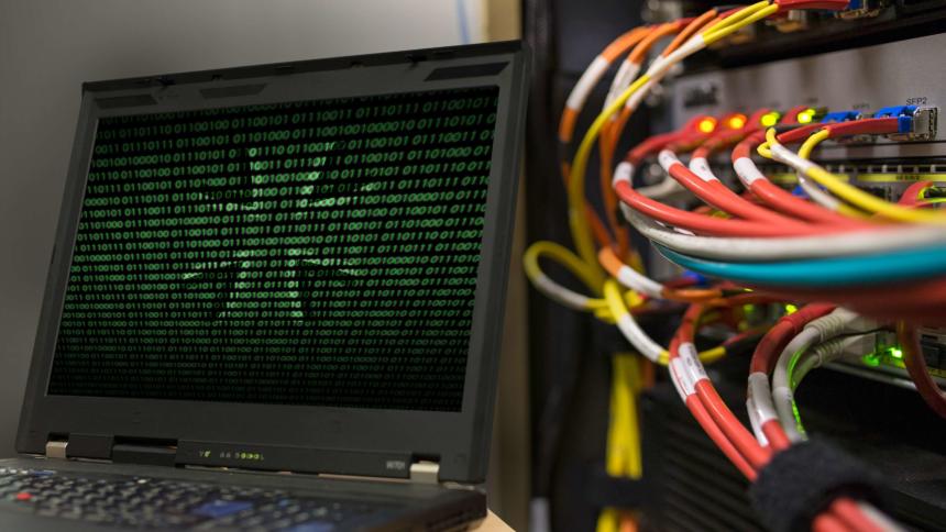 Bildmontage zeigt Kabelanschlüsse an einem Rechner und das Eiserne Kreuz hinter einem Binärcode auf einem Laptop