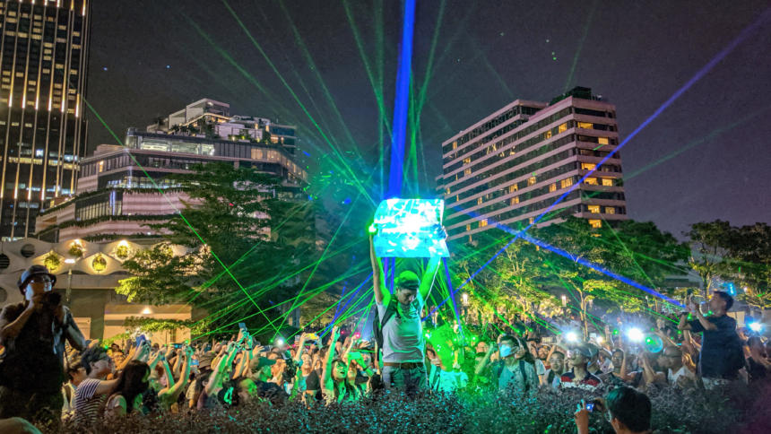 Menschen protestieren in Hongkong mit Laserpointern, im Hintergrund Hochhäuser