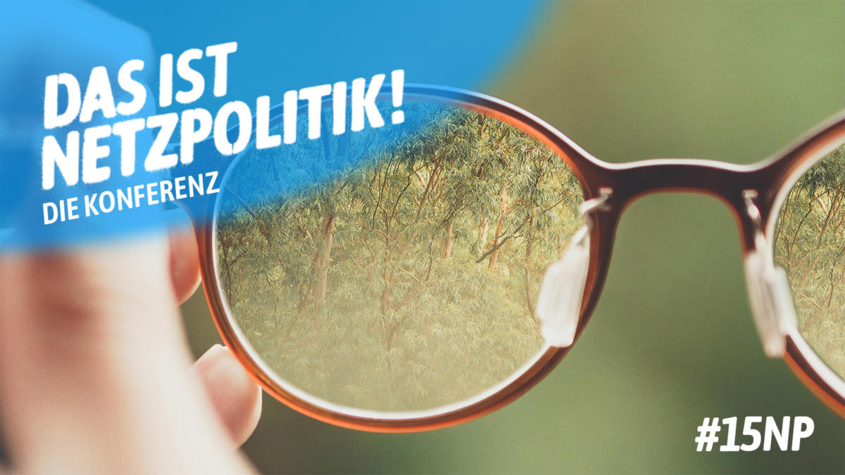 Hände halten Brillen, in denen sich Wald spiegelt