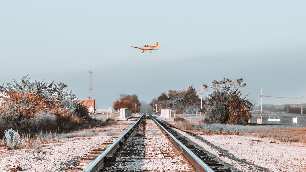 Flugzeug fliegt über Bahnschienen