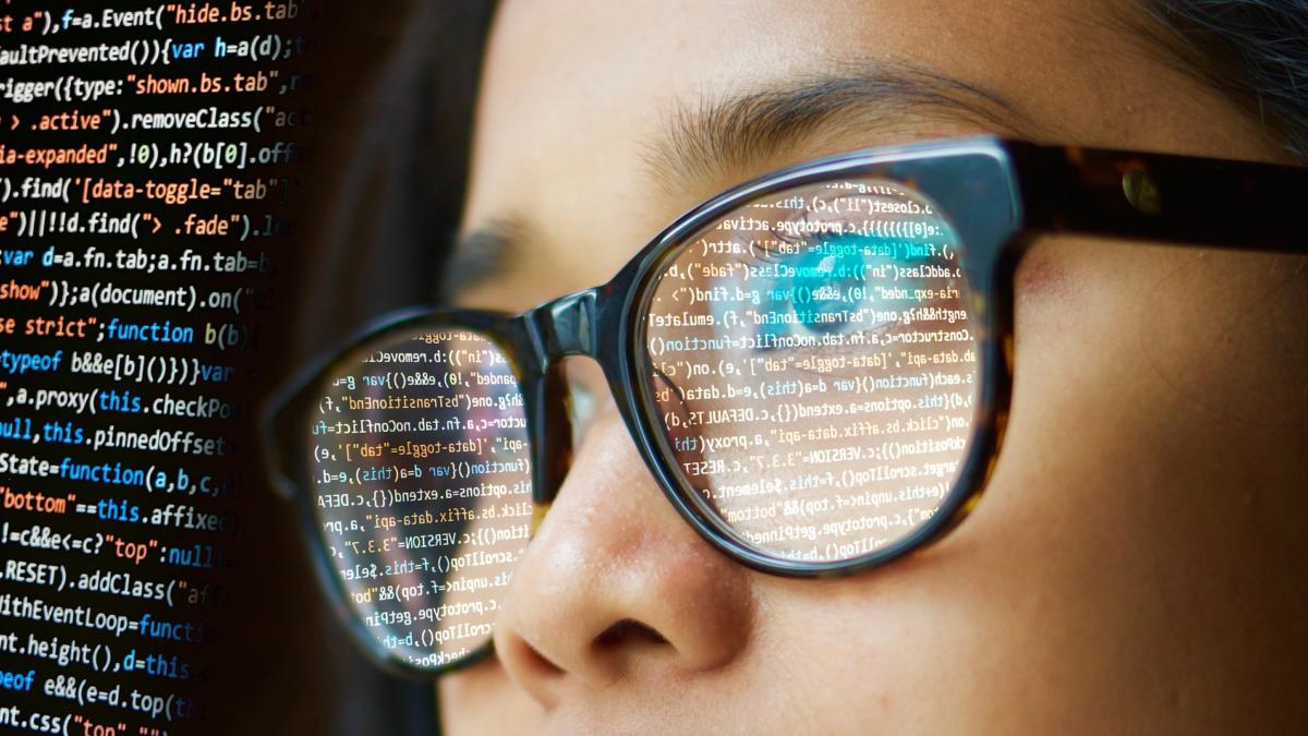 Frau mit Brille in der sich Code spiegelt