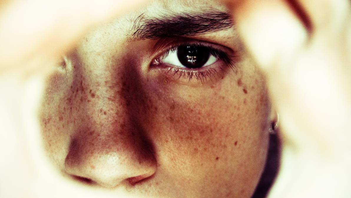 Ein Auge, dass durch einen Ausschnitt von Händen blickt