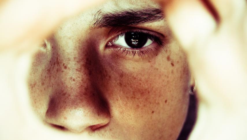 Ein Auge, dass durch einen Ausschnitt von Händen blickt