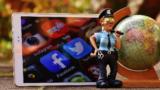Polizistenfigur neben Smartphone und Spielzeug-Globus
