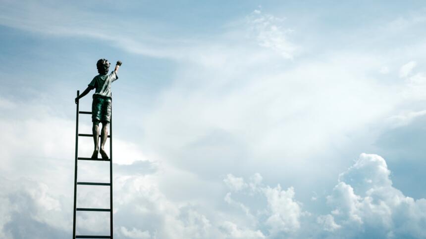 Ein Kind steht hoch oben auf einer Leiter