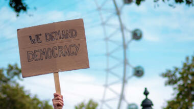 Schild mit der Aufschrift "We demand Democracy"