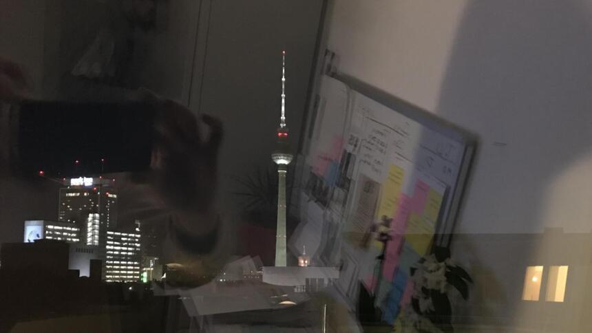 Berliner Fernsehturm aus einem Fenster, in dem man die Spiegelung sieht