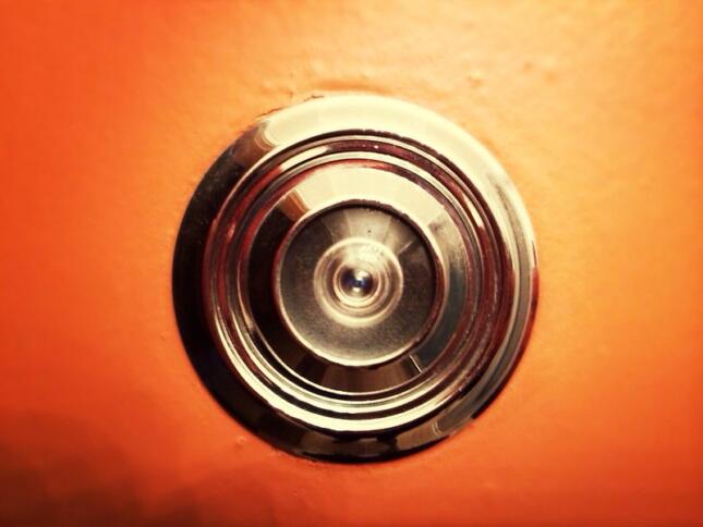 Ein türspion auf einer rot lackierten Tür ist zu sehen.