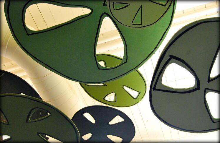 Eine Nahaufnahme mehrerer aus Pappe ausgeschnittener Zahnräder in verschiedenen Grüntönen.