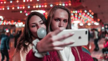 Zwei junge Frauen machen ein Selfie vor Kirmenhintergrund