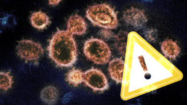 Warnschild auf Mikroskopaufnahme von Coronavirus