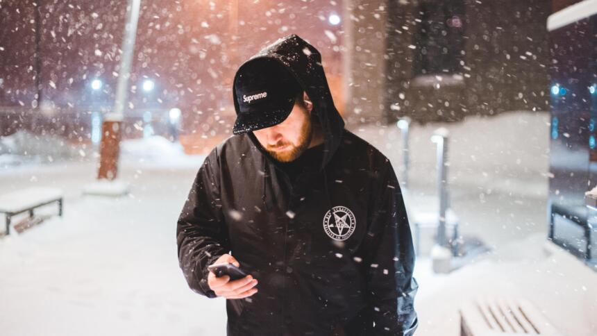 Mann schaut im Schnee auf sein Smartphone