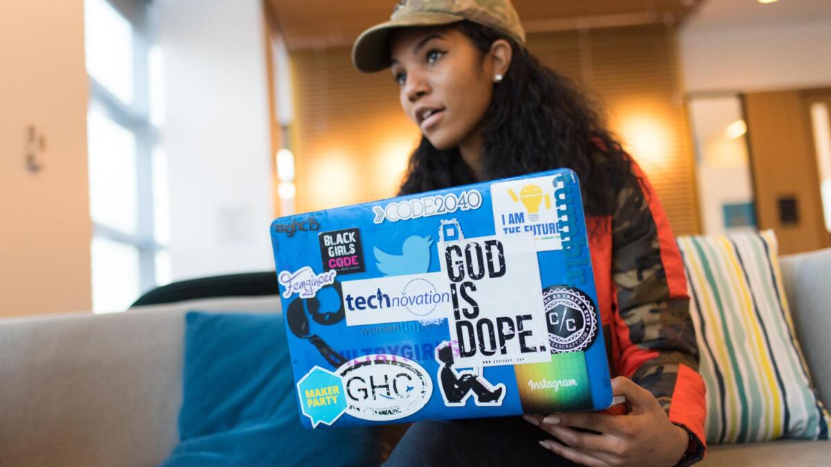 Frau sitzt hinter Laptop, der mit Stickern beklebt ist