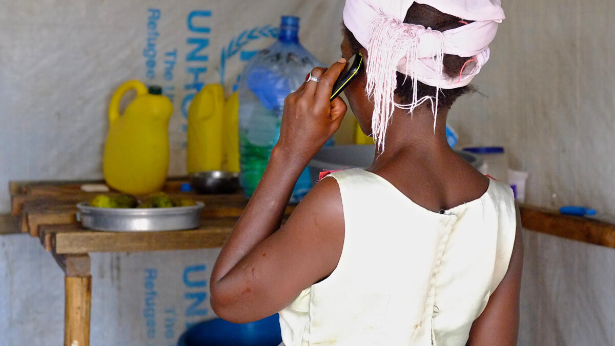 Frau in UNHCR-Camp mit Telefon