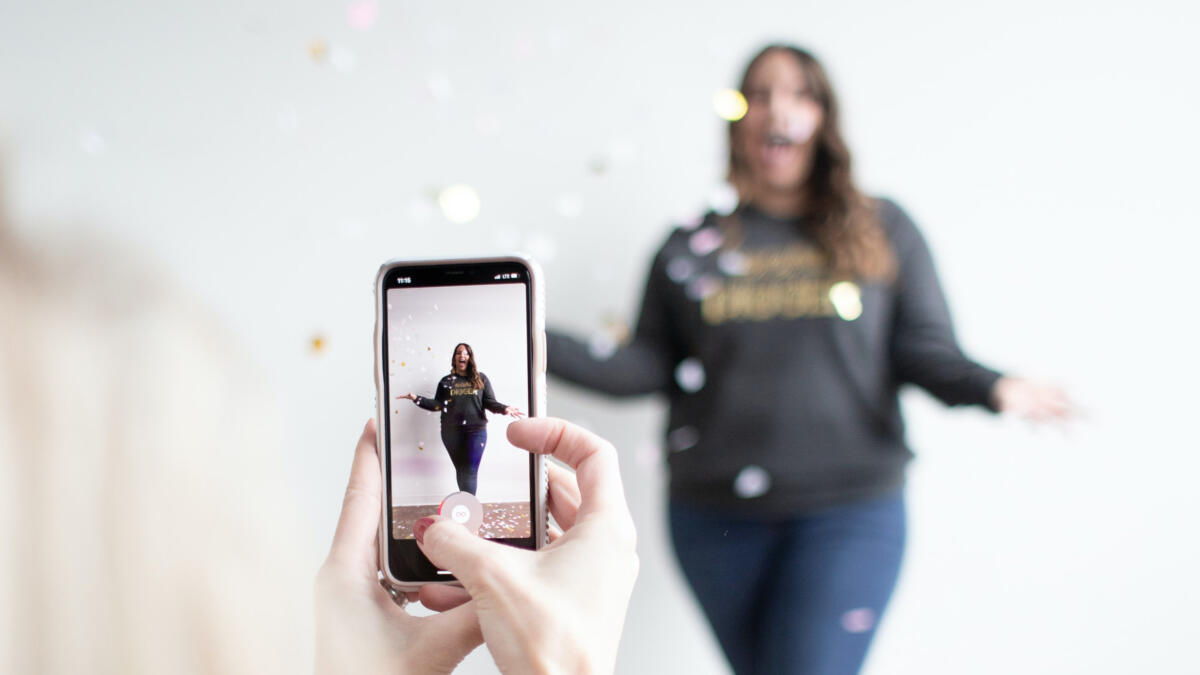 Frau filmt Frau im Hochformat, Konfetti ist in der Luft