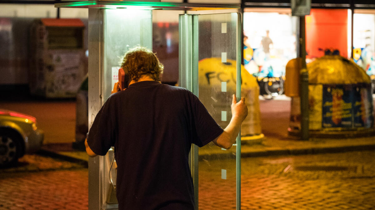 Mann telefoniert in Telefonzelle