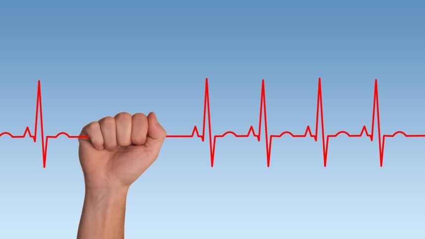 Eine Hand greift nach einer EKG-Kurve.