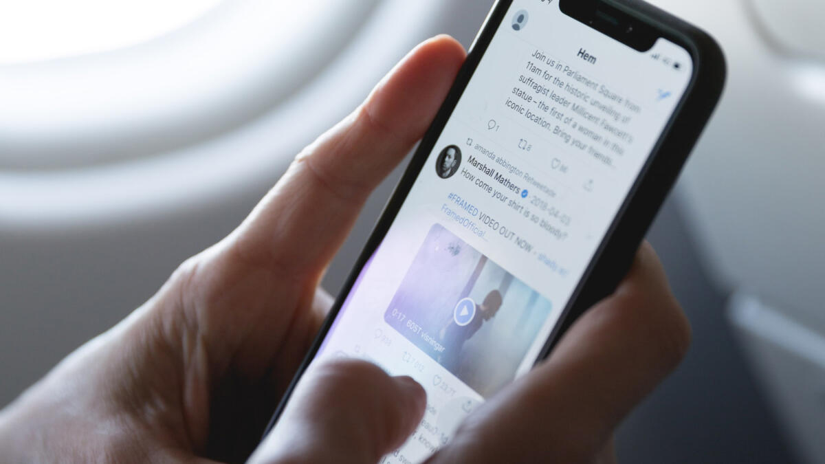 Mensch hält Smartphone in der Hand, auf dem Twitter zu sehen ist