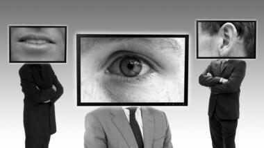 Drei Personen, die statt eines Kopfes je einen Bildschrim mit einem Mund, einem Auge oder einem Ohr tragen.