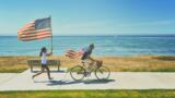 Kinder fahren und laufen am Strand mit US-Flaggen