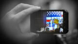Ein Smartphone filmt Donald Trump vor einer großen US-Flagge