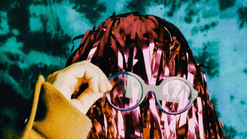 Person mit Lametta-Haaren setzt sich nerdige Brille auf