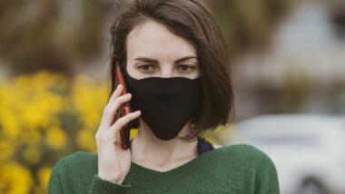 Ein Mensch telefoniert am Handy mit Maske
