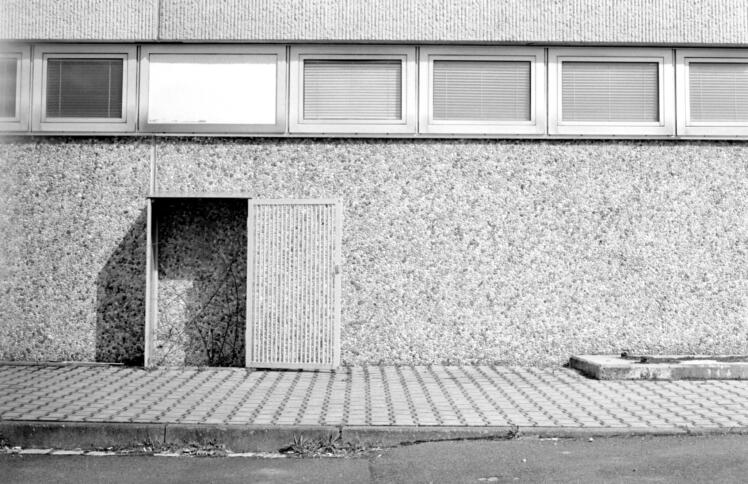 Eine Hintertür, die auf eine Betonwand stößt, schwarz-weiß-Bild