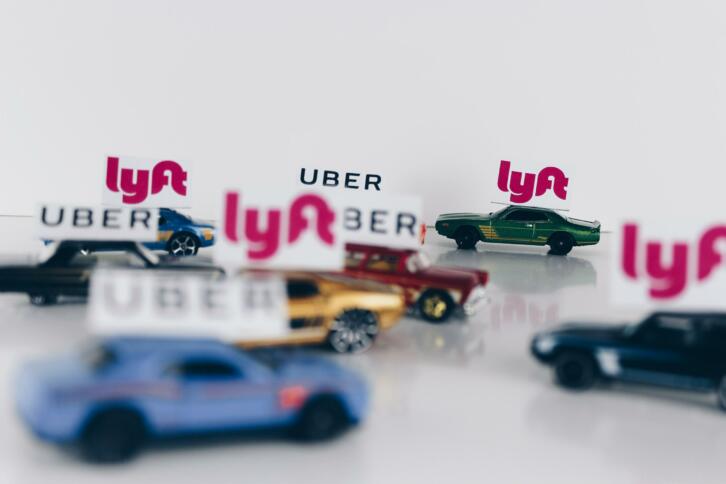 Spielzeugautos mit kleinen Flaggen der Logos von Lyft und Uber.