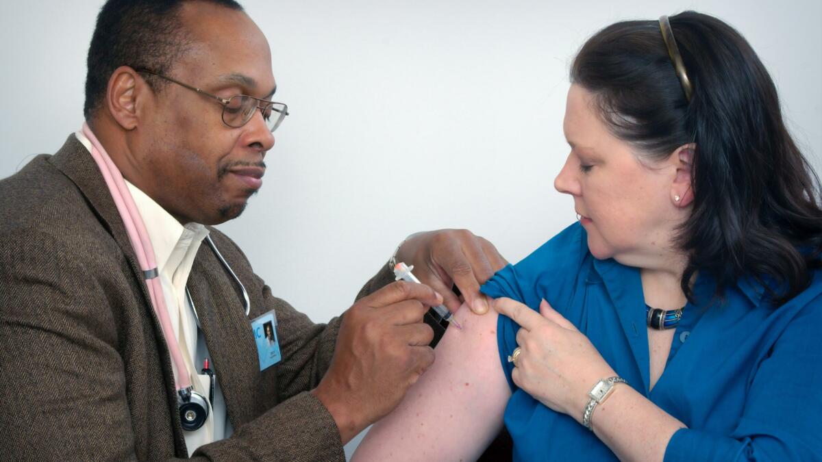 Mann gibt einer Frau eine Spritze in den rechten Oberarm.