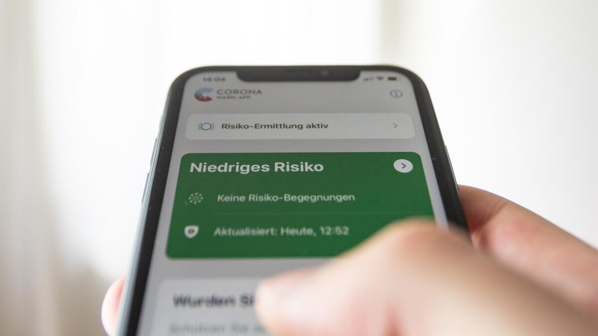 Smartphone mit geöffneter Corona-Warn-App mit niedrigem Risiko.
