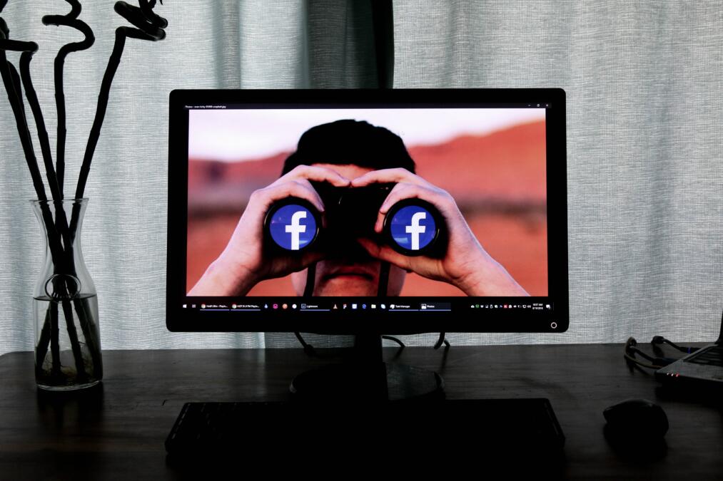 Mann guckt durch Fernglas mit Facebook Logo