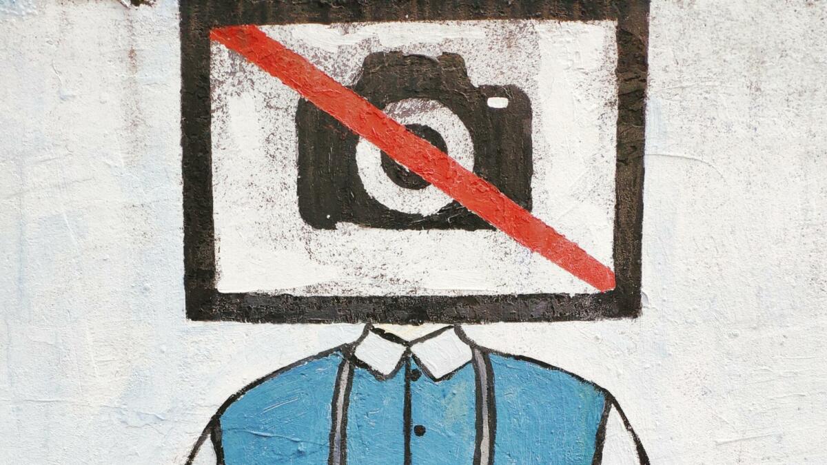 Graffiti mit durchgestrichener Kamera vor dem Kopf einer Person