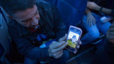 Ein Mann zeigt Bilder seiner Heimatstadt auf dem Smartphone