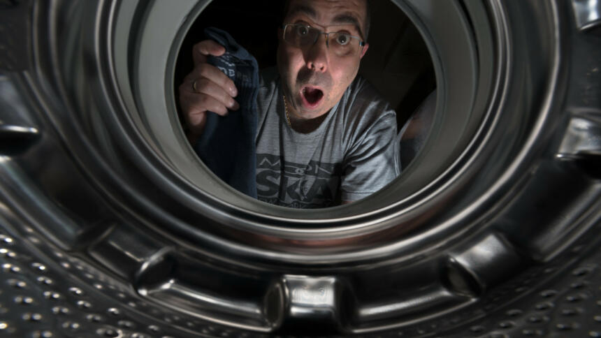 Mensch schaut in eine Waschmaschinentrommel