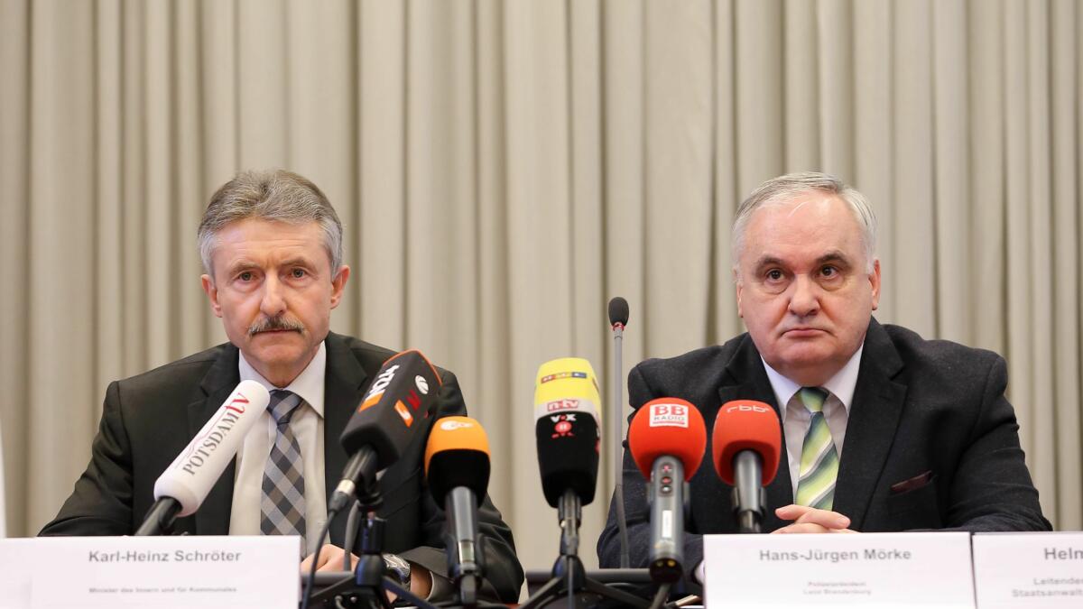 Zwei weiße Männer in dunklen Anzügen blicken grimmig.